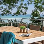 Terrasse mit Tisch und Stühlen, Blick auf das Meer und Bäume.