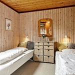 Zwei Einzelbetten mit weißen Bettwäschen, Holzwände und ein Schrank mit Körben.