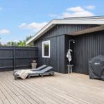 Terrasse mit Liegestühlen, Dusche und Grill, umgeben von Holzgeländern.