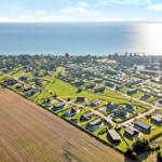 Aerial view of a coastal village with houses, fields, and the sea.