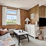 Ein Raum mit Holzwänden, Fenster, Sofa, Couchtisch und Fernseher.