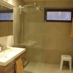 Badezimmer mit Toilette, bodentiefer Dusche, Wandwaschbecken und 2 Schubladen, in denen sich Handtücher und diverse andere Dinge befinden