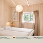 Schlafzimmer mit Doppelbett, Holzwandverkleidung und Fenster mit Vorhängen.