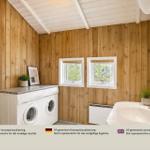Wohnung mit Holzwänden, Waschmaschine, Waschtisch und zwei Fenstern.