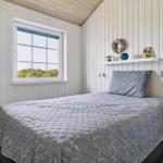 Schlafzimmer mit Bett, Fenster und Nachttisch. Wandverkleidung und Holzdecke.