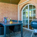 Terrasse mit Tisch, Stühlen, Grill und Blick ins Haus.