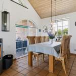 Esszimmer mit Holztisch, Rattanstühlen und Kaminofen. Terrasse über Glastür zugänglich.