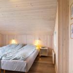 Schlafzimmer mit Doppelbett, Holzwandverkleidung und Wandbildern