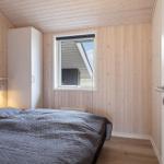 Schlafzimmer mit Holzwand, Bett und Fenster. Tür und Kleiderschrank sind sichtbar.