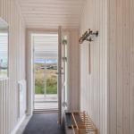 Hausflur mit Holzwand, Spiegel und Tür zum Balkon. Holzstuhl und Haken an der Wand.
