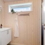 Badezimmer mit Holzwand, Waschbecken, Spiegel und Fenster