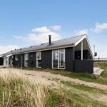 Moderne, schwarz getäfelte Villa mit großem Fenster und Dachgaube im Grasland.