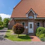 Haus mit Ziegeldach, weiße Tür und gepflegtem Vorgarten mit Rasen und Bäumen.
