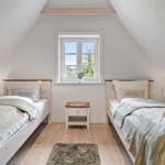 Zwei Betten in einem Dachzimmer mit Fenster und Holzboden.