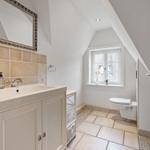 Badezimmer mit Waschbecken, Spiegel, Toilette und Fenster.