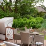 Terrasse mit Loungemöbeln, Tisch und Flasche Champagner im Garten.