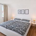 Schlafzimmer mit Doppelbett, Fenster, Nachttischen und Kinderbett.