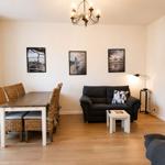 Wohn- und Essbereich mit Sofa, Esstisch und Wandbildern.