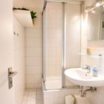 Badezimmer mit Dusche, Waschbecken und Spiegel.