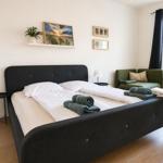 Schlafzimmer mit Doppelbett, grünem Sofa und Fenster mit Blick.