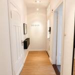 Flur mit Holzboden, weißen Türen und Wandgarderobe. Spiegel reflektiert den Raum.