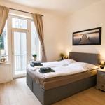 Schlafzimmer mit Doppelbett, Fenster zur Terrasse und Nachttischen mit Lampen.