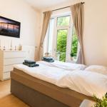 Schlafzimmer mit Doppelbett, Fenster mit Blick auf Garten und weiße Kommode mit Kerzen.