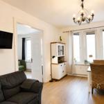 Wohn- und Essbereich mit Sofa, TV, Esstisch und Fenstern.