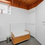 Badezimmer mit Toilette, Holzbank und Fenster mit Seesternmotiv.