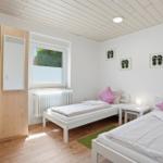Zwei Einzelbetten, Schrank, Fenster und Wanddekoration mit Flipflops.