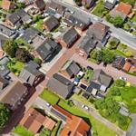 Luftbild eines Wohngebiets mit Häusern, Grünflächen und Straßen.