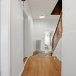 Flur mit Holzboden, Treppe und Heizkörper. Weiße Wände und Decke.
