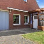 Rotes Backsteingebäude mit Garage, Terrasse und Gartenbereich.