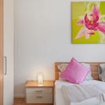 Schlafzimmer mit Bett, Nachttisch und Wandbild einer Orchidee.