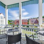 Terrasse mit Tisch, Stühlen und Blick auf Häuser und Grünflächen.