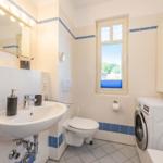 Badezimmer mit Waschmaschine, Toilette und Fenster