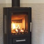 Holzofen mit brennenden Holzscheiten an der Wand