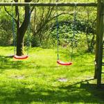 Hinterhof mit Spielplatz, Schaukel und Rutsche auf grünem Rasen.
