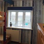 Zimmer mit Doppelstockbett, Fenster und Holzmöbel. Auf Schreibtisch steht ein gelber Bus.