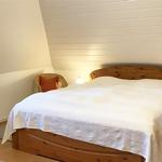 Schlafzimmer mit Holzbett, Nachttischen und Fenster. Wandverkleidung und Heizung sichtbar.