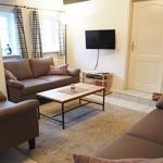 Wohnzimmer mit Sofa, Sessel und Fernseher an der Wand.