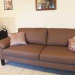 Ein braunes Sofa mit Kissen steht vor einer Wand mit Kaminofen und Bildern.