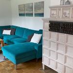 Wohnzimmer mit türkisfarbenem Sofa, Holztisch und dekorativem Kamin.