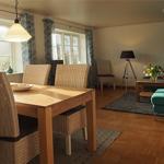 Essbereich mit Holztisch und Stühlen. Wohnbereich mit Sofa und Beistelltisch.