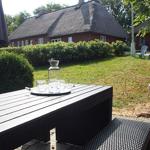 Außenbereich mit Tisch, Stühlen und Grill. Im Hintergrund ein traditionelles Haus mit Schindeldach.