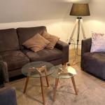 Wohnzimmer mit braunem Sofa, Sessel, Glas-Tisch und Stehlampe.