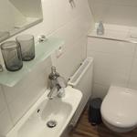 Badezimmer mit Waschbecken, Spiegel, Toilette und Handtuchhalter.
