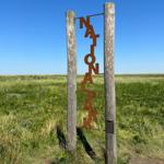 Nationalpark-Schild zwischen zwei Holzpfosten im Grasland unter blauem Himmel
