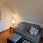 Ein Sofa mit Kissen, Beistelltisch und Lampe unter schrägem Dach.