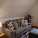 Ein Sofa mit Kissen, Beistelltisch und Lampe unter einem Dachschrägen.